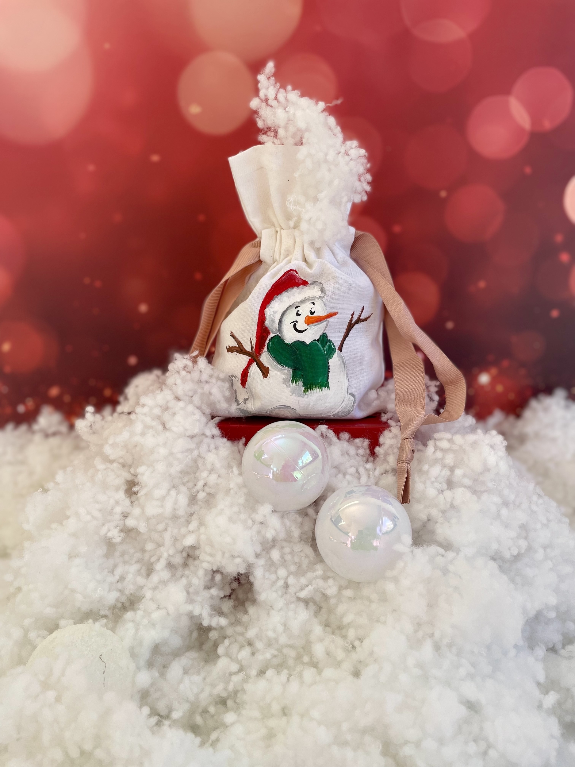 Pochon en coton blanc et ruban de satin rose avec un bonhomme de neige portant un bonnet de Père Noël peint à la main par Elles et No.