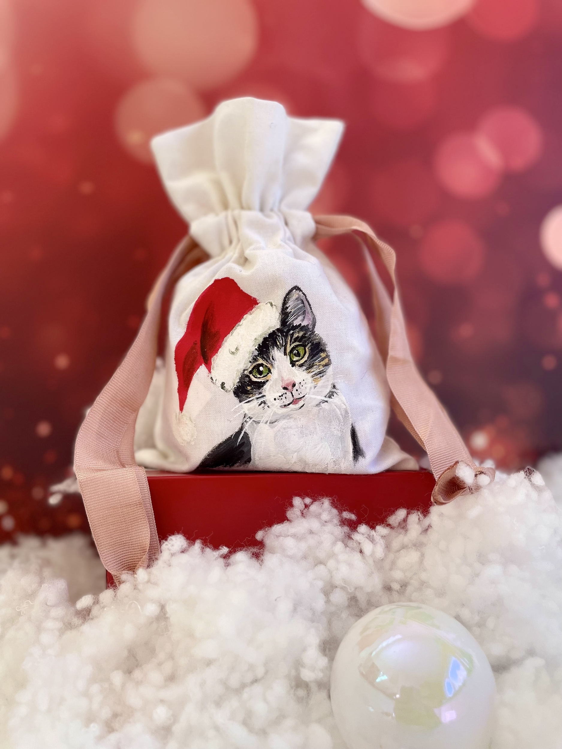 Pochon en coton blanc et ruban de satin rose avec un chat portant un bonnet de Père Noël peint à la main par Elles et No.