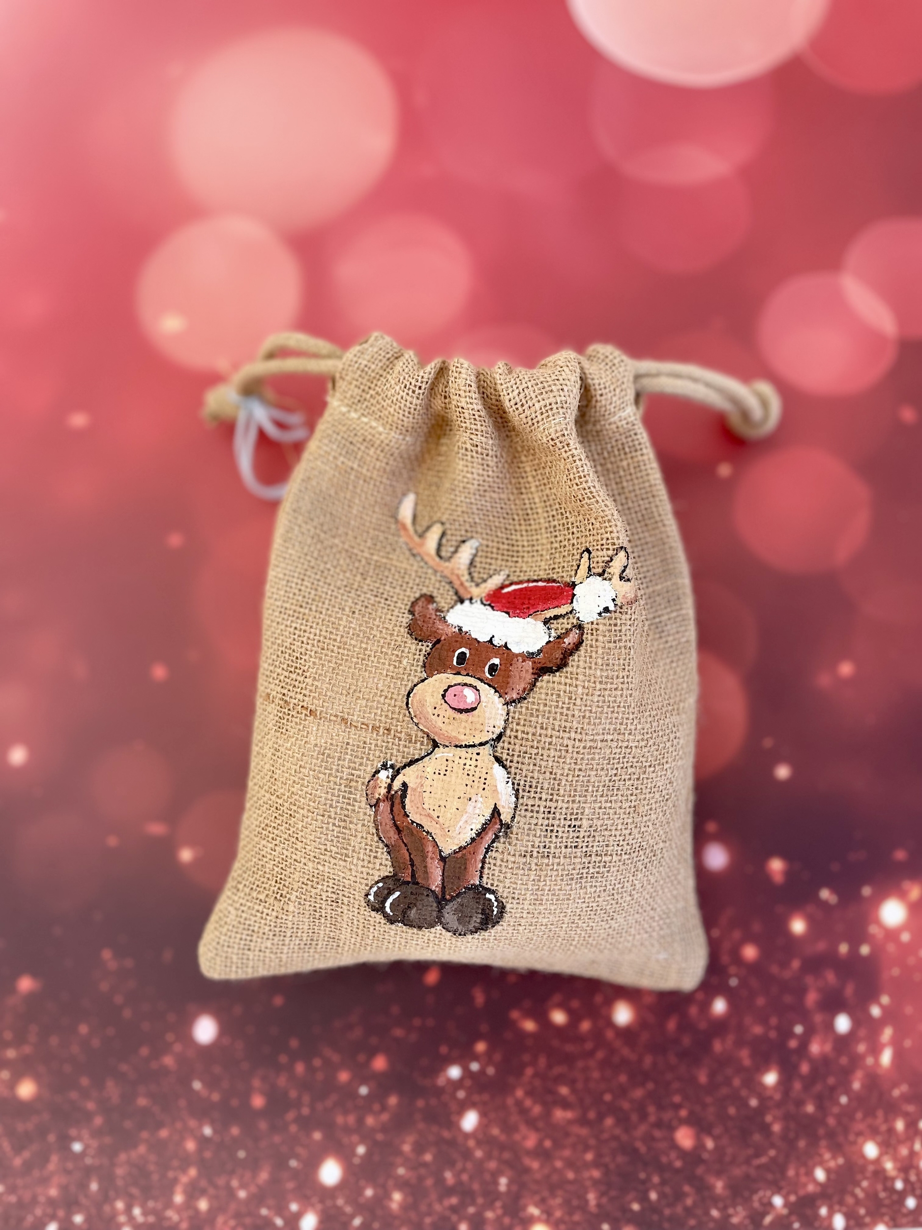 Pochon en jute avec un renne coiffé dun bonnet de père Noël peint à la main par Elles et No.