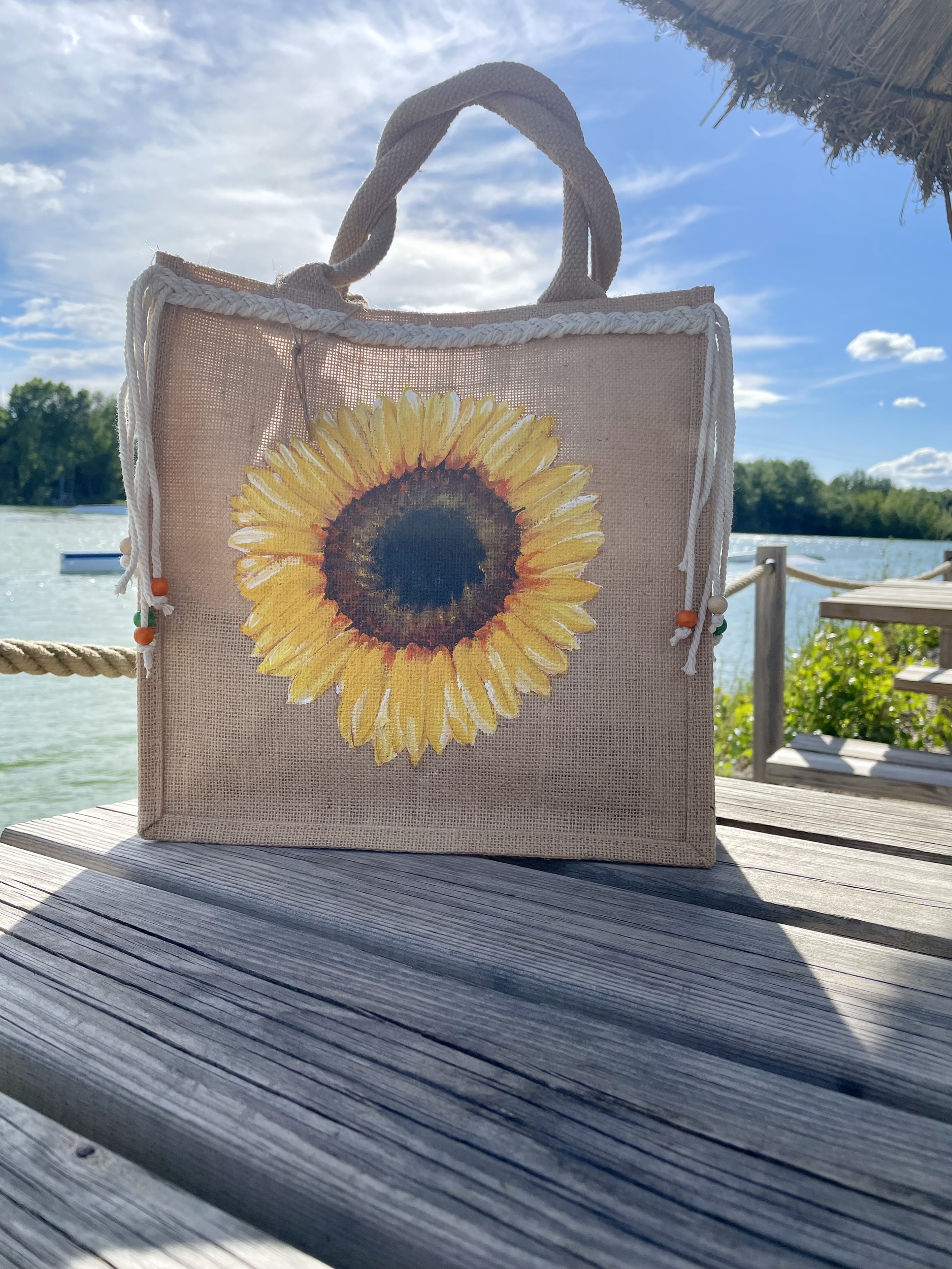 sac en jute avec un gros tournesol peint à la main par Elles et No. et un décor en macramé tressé et des perles
