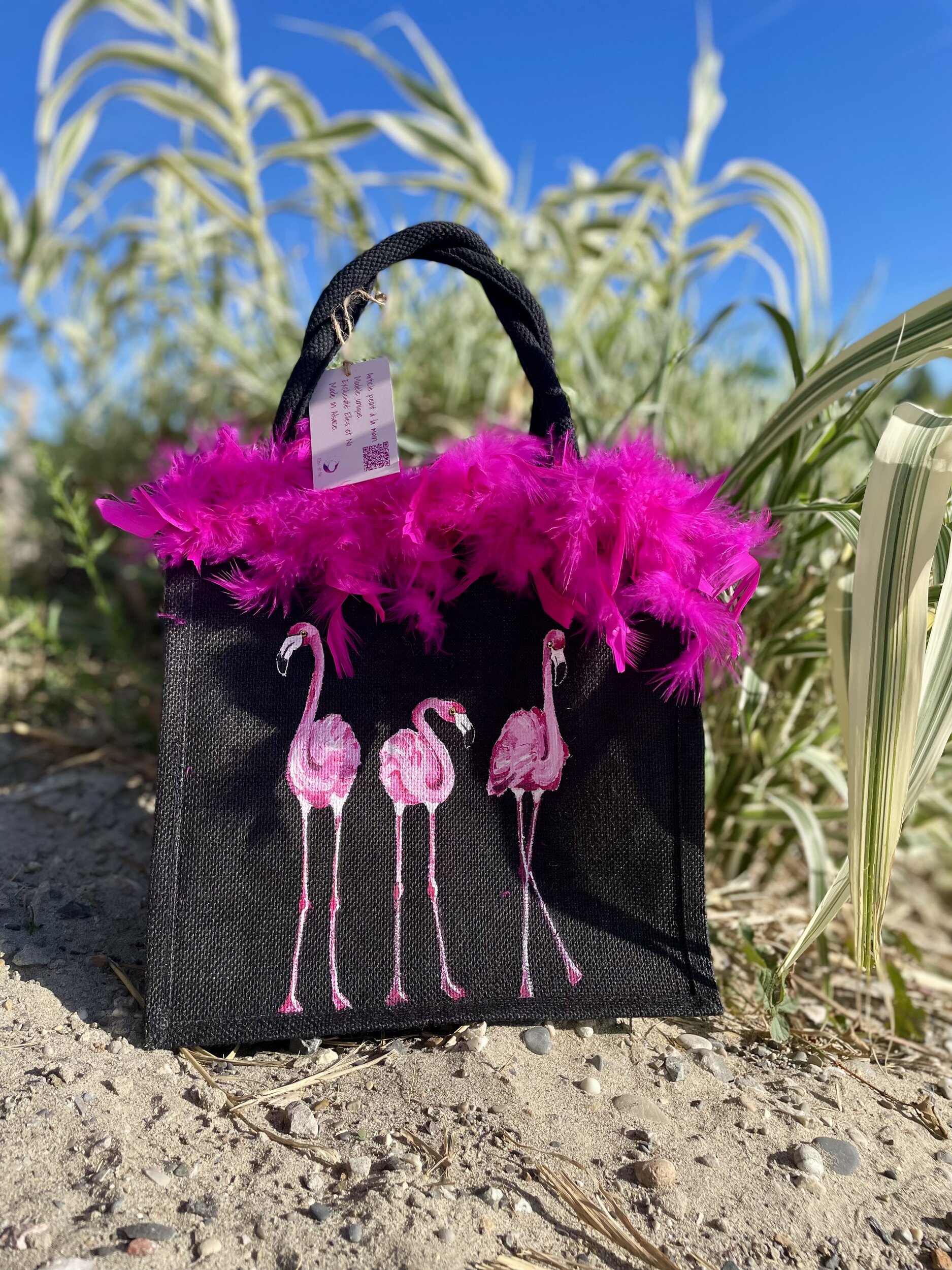 sac en jute noire avec des flamants roes peints à la main par Elles et No. et un boa rose en vraies plumes collé sur le bord.j