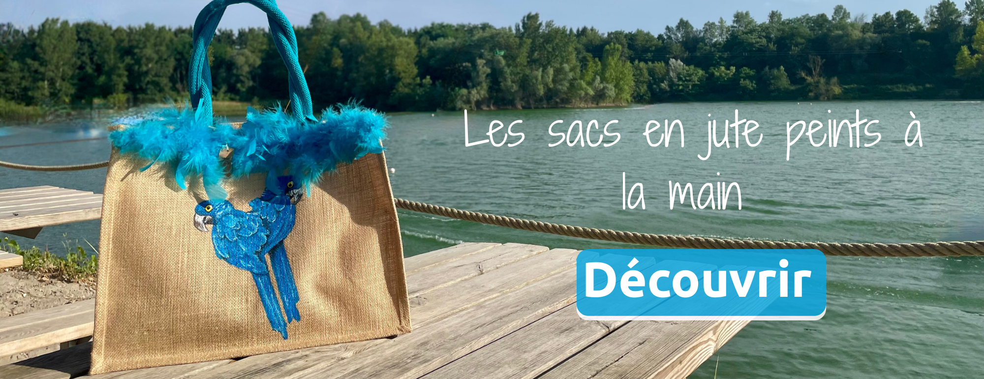 présentation de la collection de sacs peints à la main par Elles et No. le sac perroquets bleus et son boa en vraies plumes est présenté au bord de l'eau