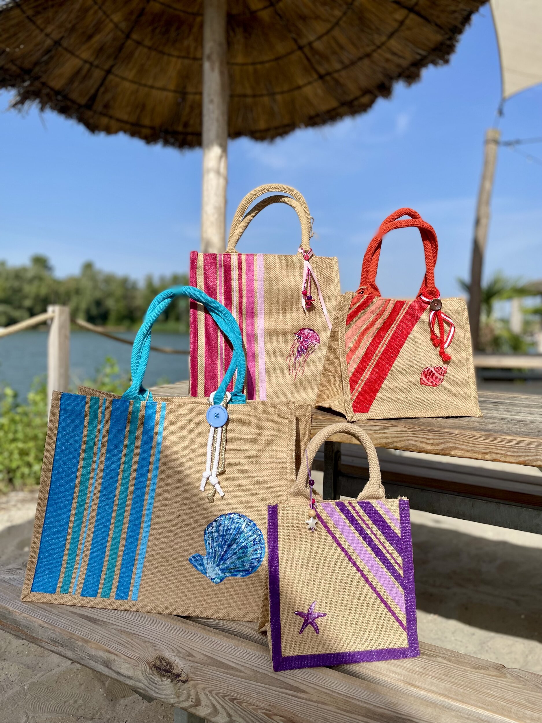 4 sacs en jute de différentes tailles avec des rayures bayadère et des motifs marins peints à la main par Elles et No., sacs présentés au bord de l'eau