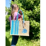 Igrand sac de plage en jute avec des bandes bayadère bleus et un coquillage peints à la main par Elle et No. Un colifichet original est attaché à la anse.
