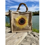 sac en jute avec un gros tournesol peint à la main par Elles et No. et décoré avec une tresse en macramé, présenté au bord de l'eau
