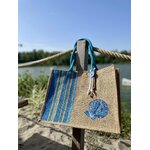 sac de plage en jute avec des rayures bayadère dans les tons bleus et un coquillage peints à la main par Elles et No., présenté au bord de leau