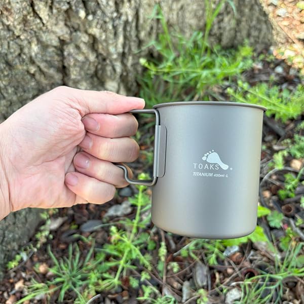 Tasse titane TOAKS tenue en main au pied dun arbre