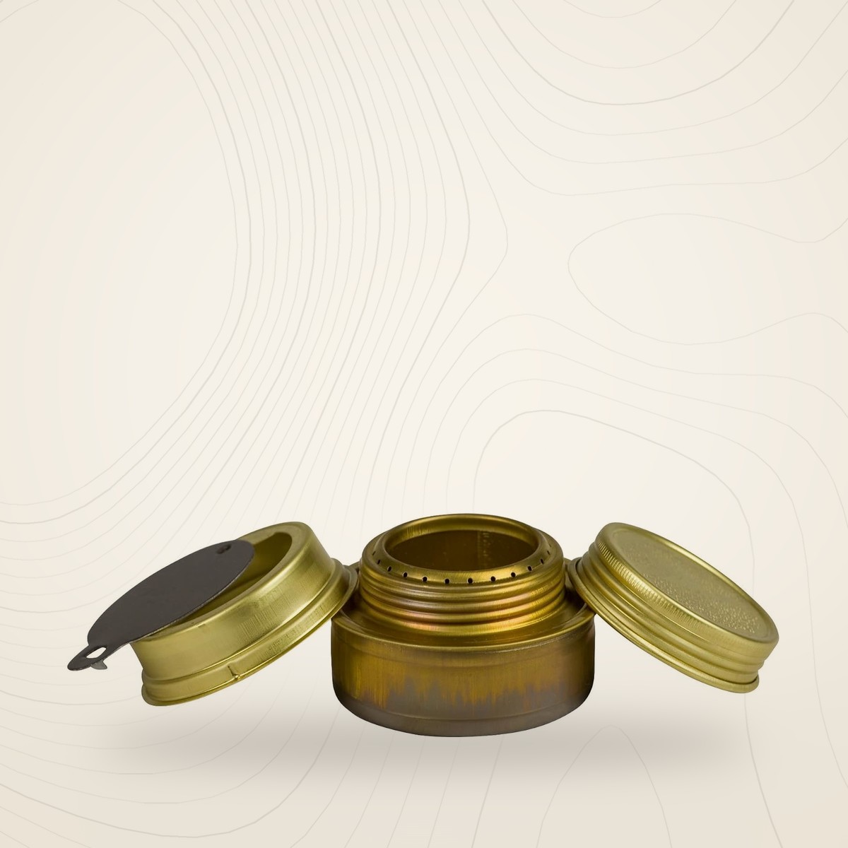 Réchaud à alcool Trangia en laiton avec couvercle à vis et bague de réglage, sur fond lin