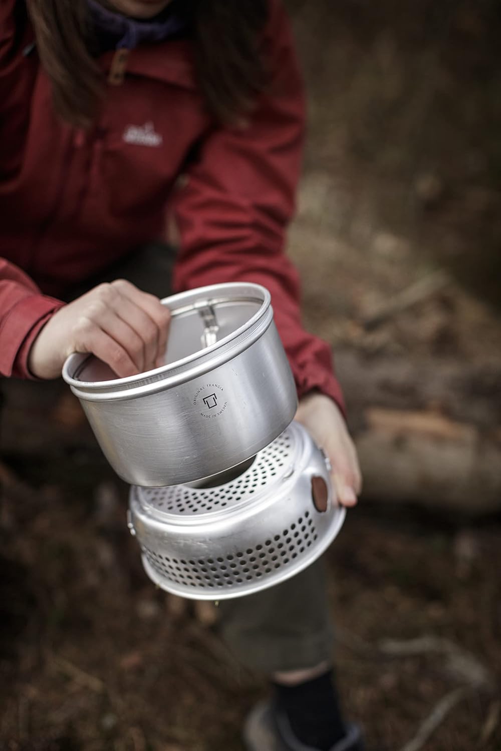 Randonneuse assemblant un réchaud Trangia 27 en forêt