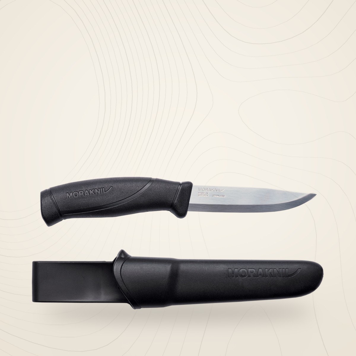 Couteau Morakniv Companion noir à lame inox, à côté de son étui en polymère noir à clip, sur fond lin