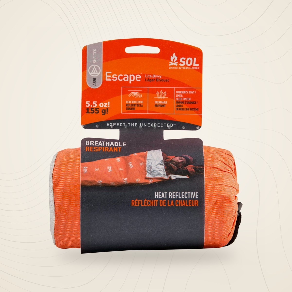 Sac de bivouac SOL Escape Lite orange roulé dans sa housse, avec son étiquette cartonnée, sur fond lin