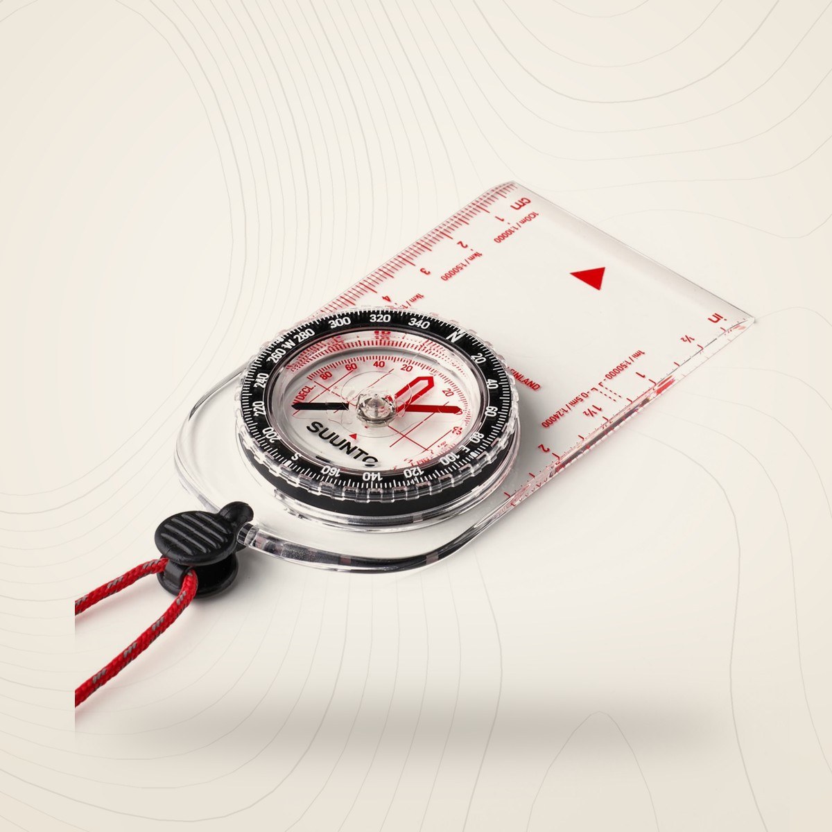 Boussole à plaquette transparente Suunto A-10 avec cordon rouge, sur fond lin