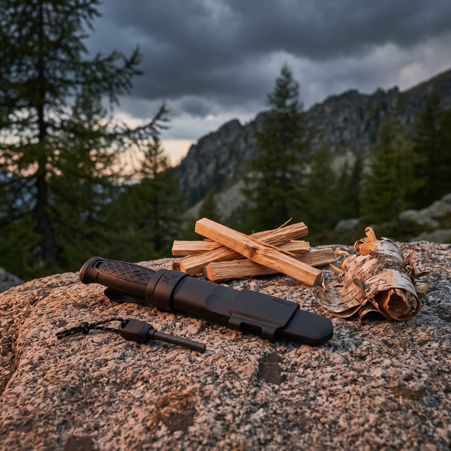 Couteau Morakniv Garberg, son étui et sa pierre à feu sur un rocher de granit près du petit bois, sous un ciel dorage