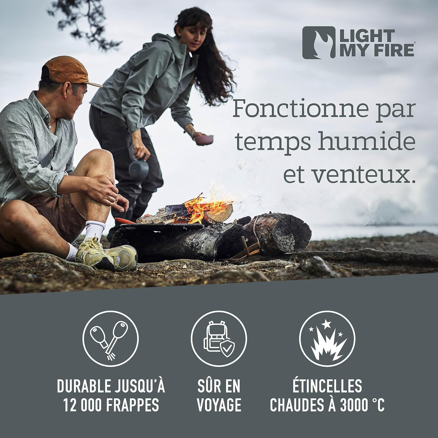 Deux campeurs près dun feu de camp allumé sur des rondins, au bord de leau