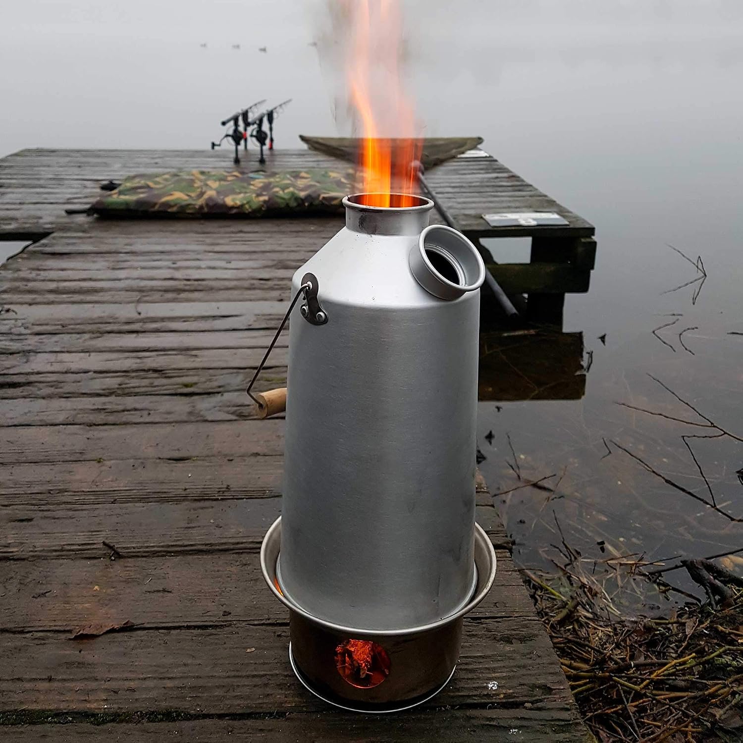 Kelly Kettle allumée sur un ponton de pêche, flammes sortant de la cheminée