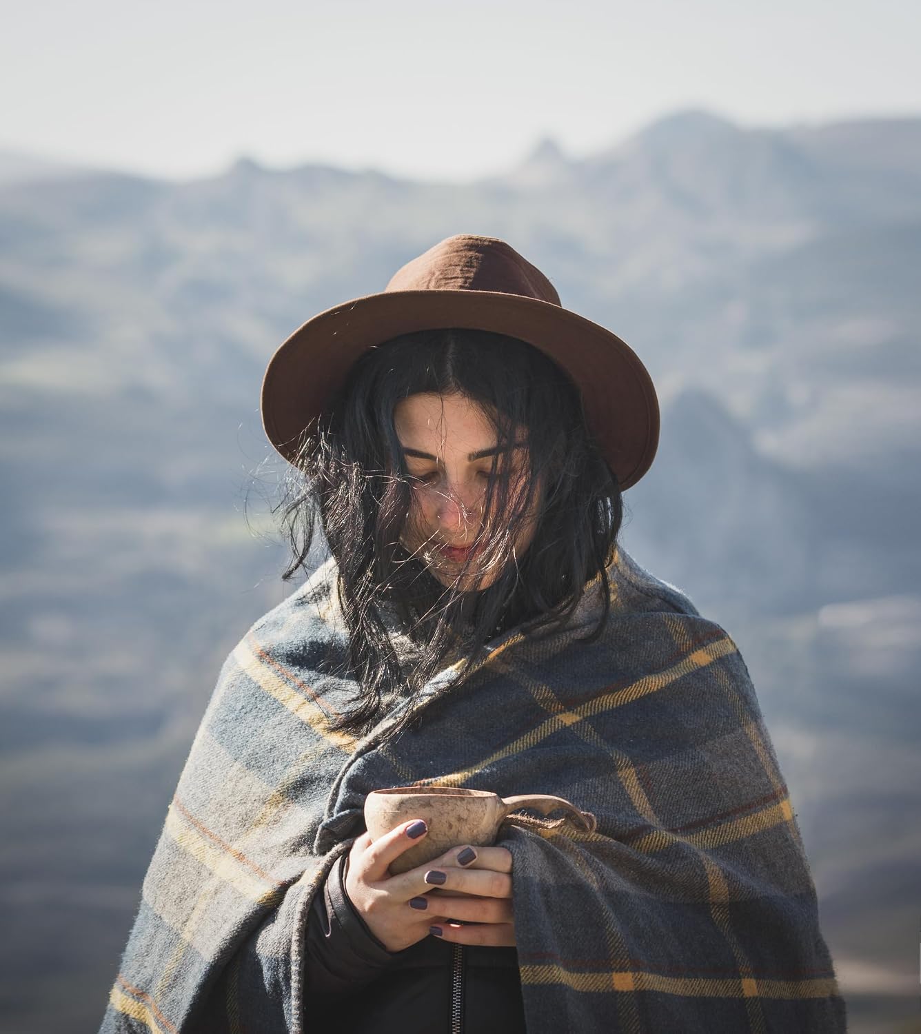 Randonneuse enveloppée dun plaid, une kuksa Kupilka dans les mains, face aux montagnes