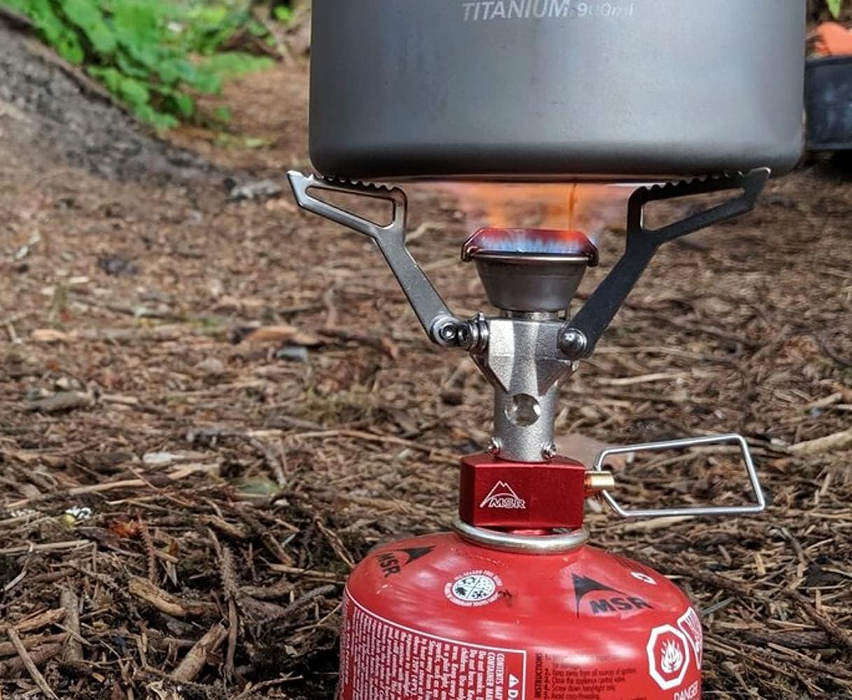 Flamme du PocketRocket 2 sous une popote en titane, sur un sol forestier