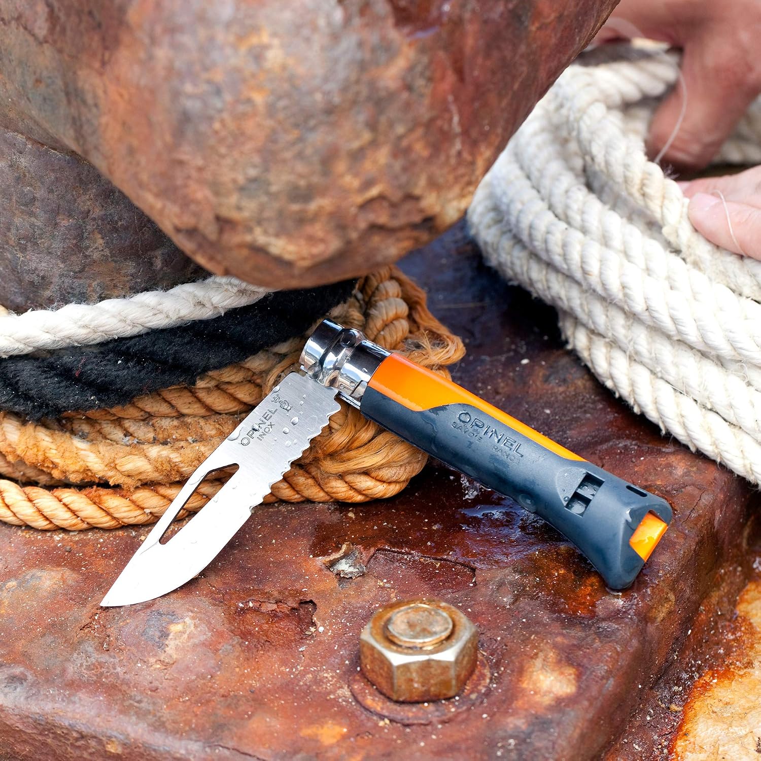 Opinel N°8 Outdoor ouvert sur des cordages mouillés, zone crantée et sifflet visibles