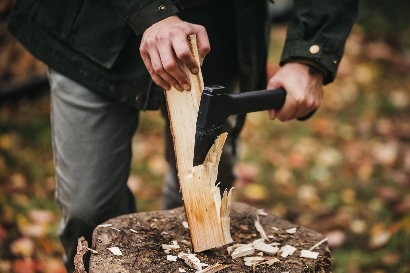 Mains fendant une bûchette avec la hachette Fiskars Solid A6 sur un billot, en forêt