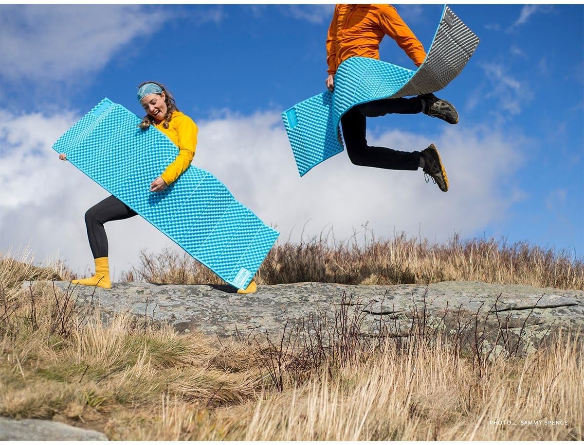 Deux randonneurs sautant sur un sommet herbeux avec leurs matelas Z Lite Sol à demi dépliés