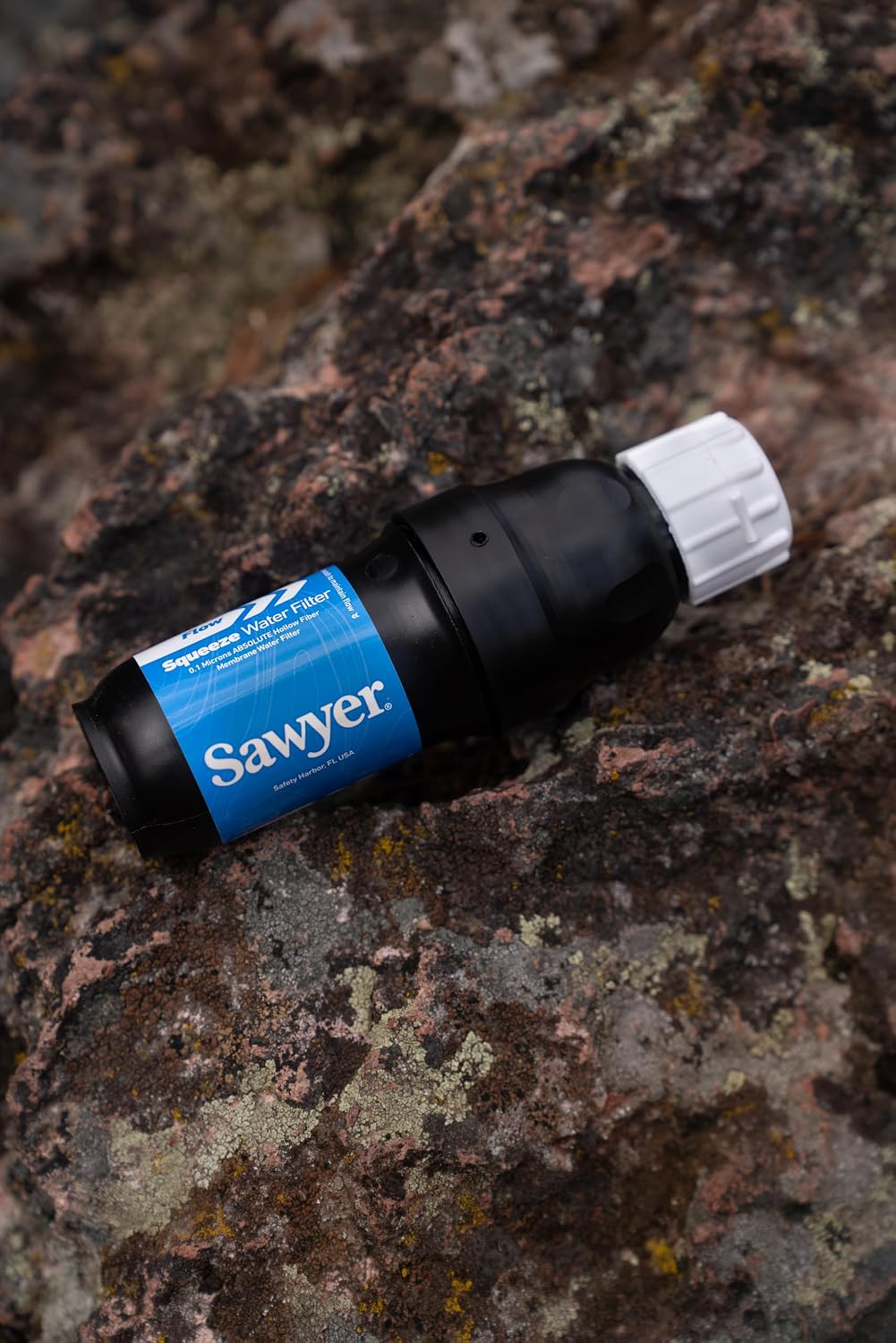 Filtre Sawyer Squeeze posé sur un rocher couvert de lichen
