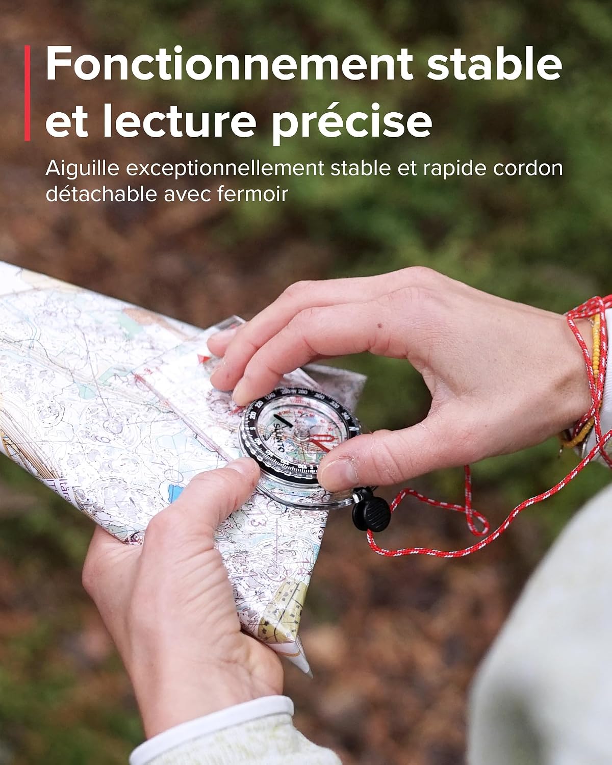 Mains orientant la boussole Suunto A-10 sur une carte topographique, cordon rouge au poignet