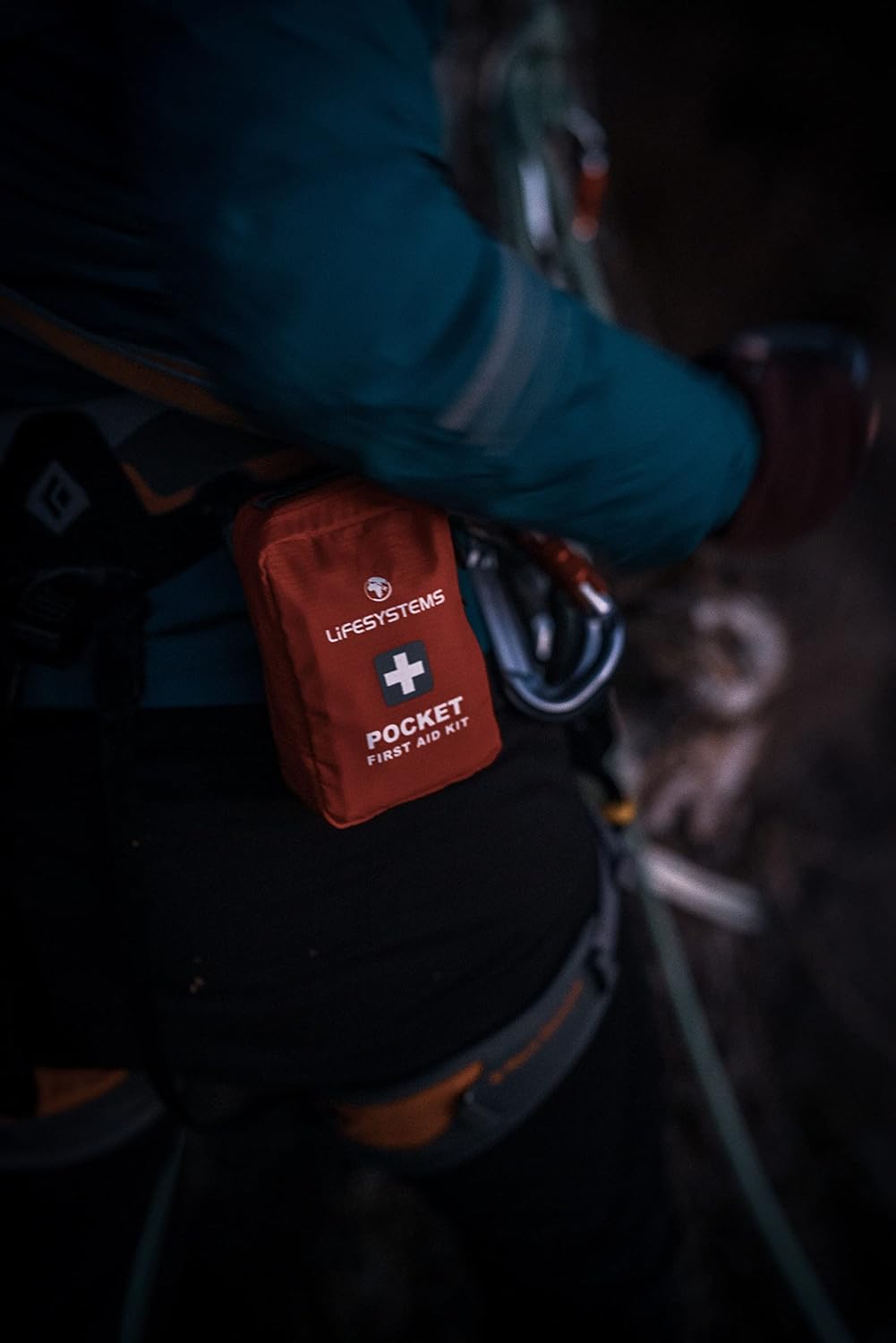 Trousse Lifesystems Pocket accrochée au baudrier dun grimpeur, à côté de ses mousquetons