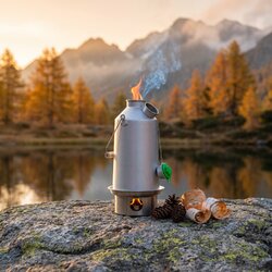 Bouilloire Kelly Kettle fumant sur un rocher au bord d'un lac d'altitude, au lever du jour