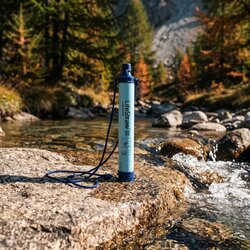 Paille filtrante LifeStraw posée sur un rocher de granit au bord d'un torrent de montagne