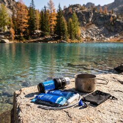 Kit de filtration Sawyer Squeeze disposé sur une dalle de granit au bord d'un lac d'altitude