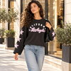 Sweat California Los Angeles noir à étoiles rose pâle, porté par une femme en ville