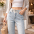 Zoom sur la ceinture en dentelle et les perles à l'avant du jean large.