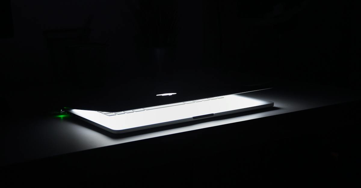 photographie de macbook a moitie ouvert sur une surface en bois blanche