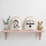 Sac pochon bébé personnalisé face dinosaure espiègle et face prénom en coton avec flocage, cadeau naissance - MARJANE et Cie