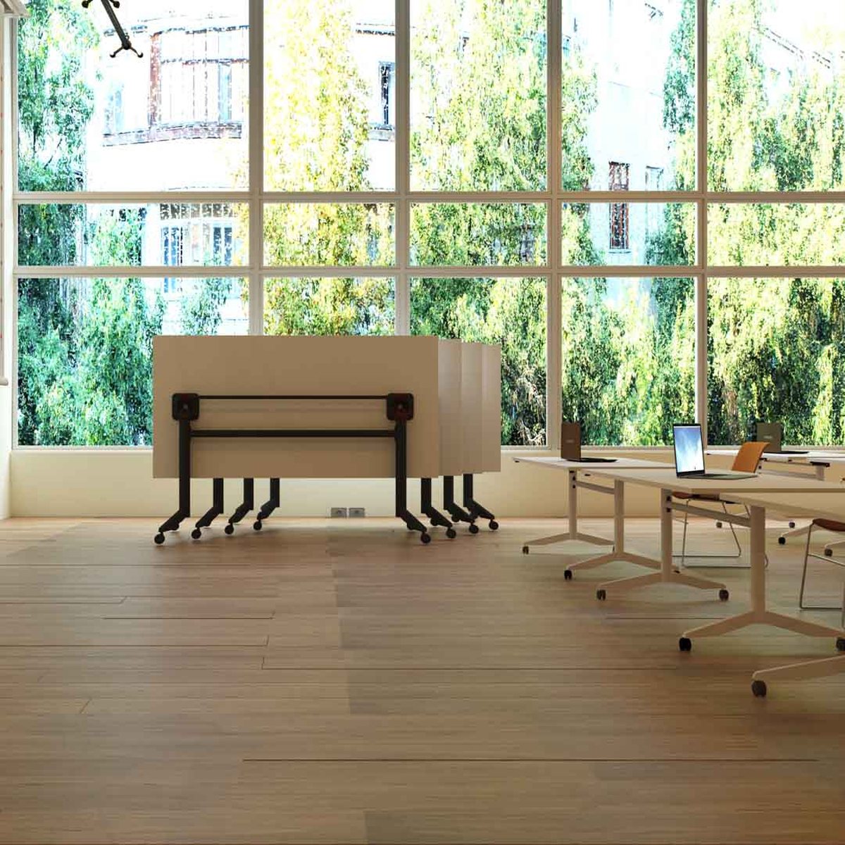 Tables pliantes repliées et emboîtées contre la baie vitrée dune salle de formation
