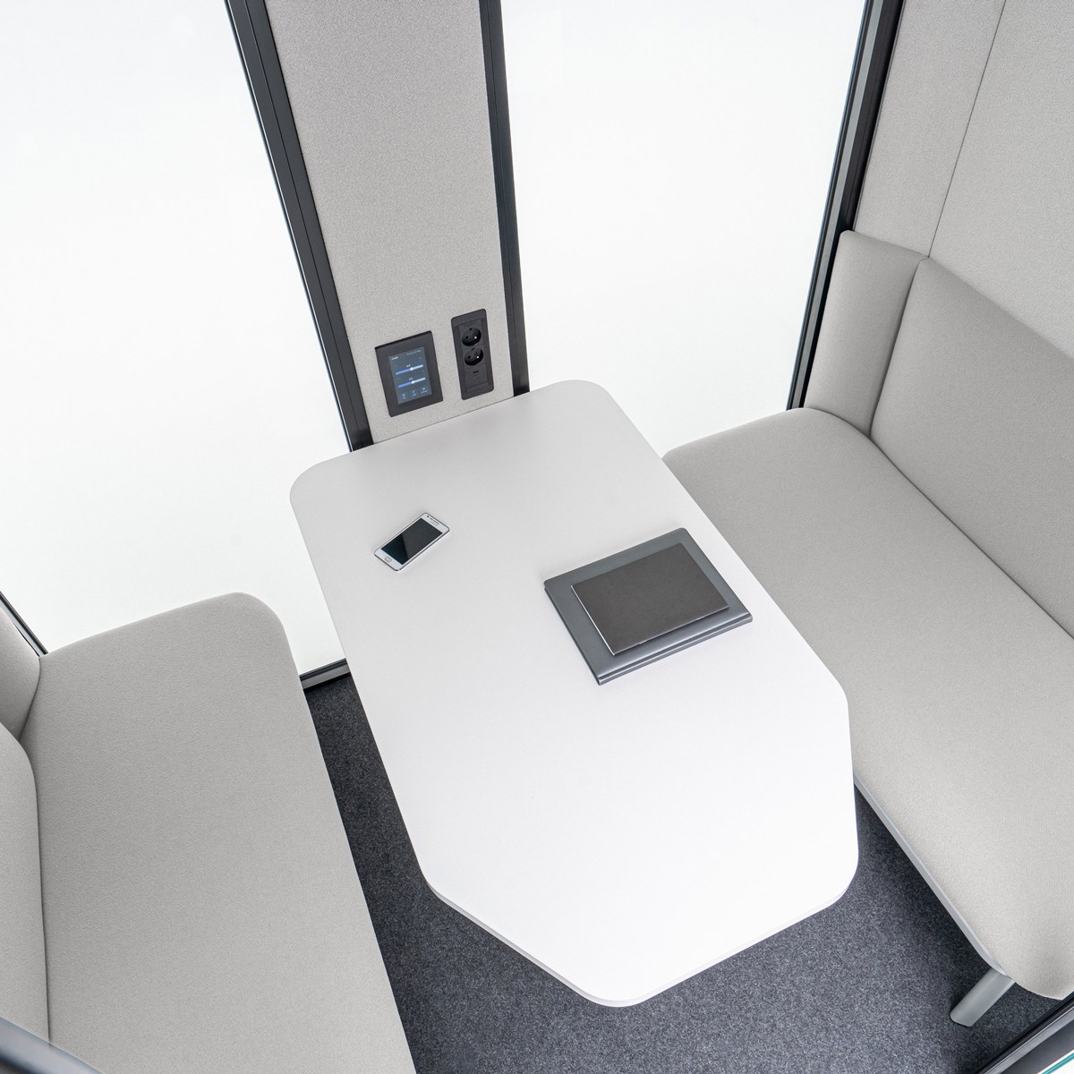 Intérieur de la cabine de réunion vu du dessus, banquettes grises et table blanche