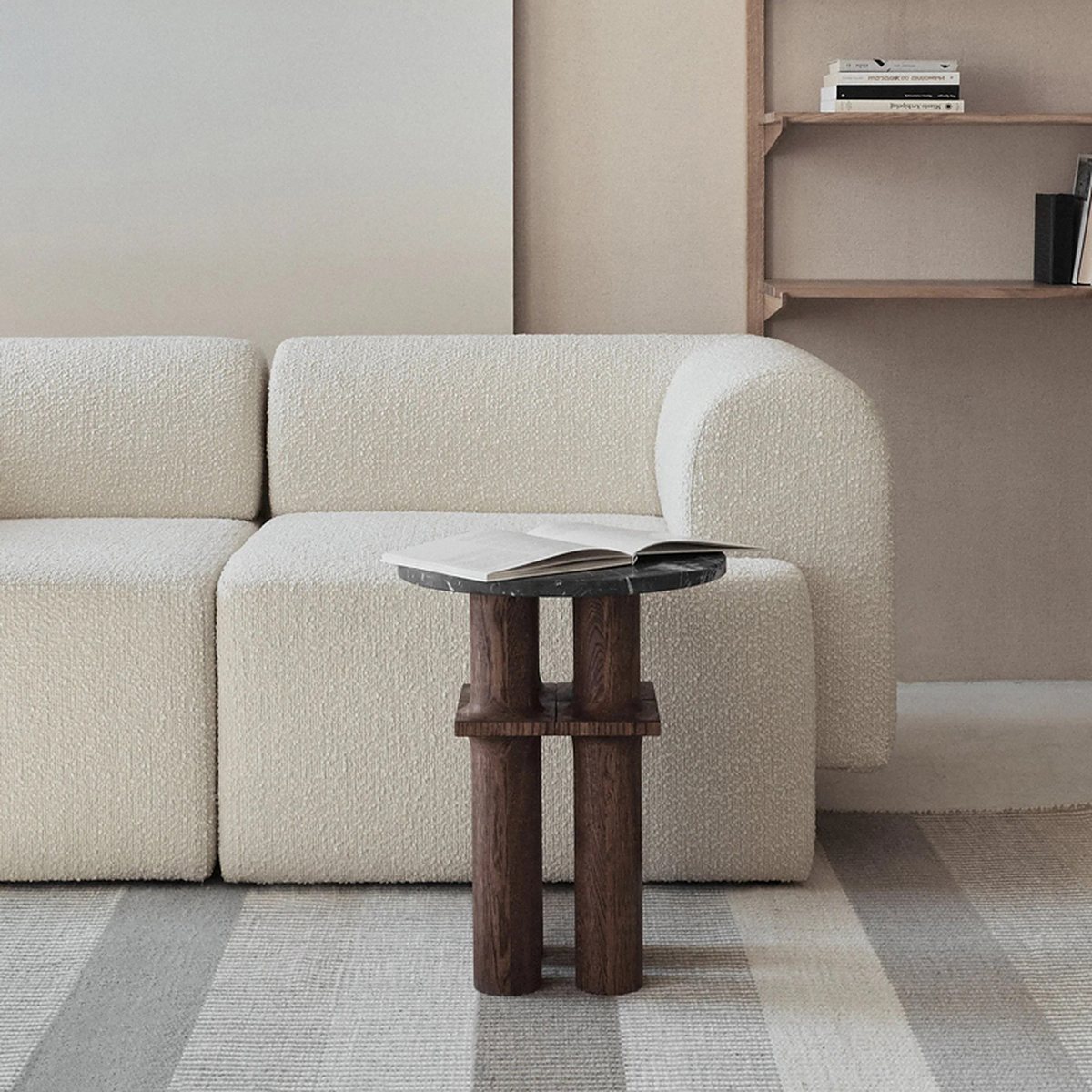 Canapé modulaire crème à base cubique devant une étagère murale