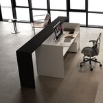 Vue plongeante sur une banque daccueil blanche à rehausse noire et son poste de travail