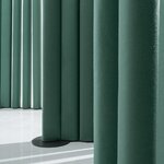 Détail des segments rembourrés en tissu vert et du socle rond noir de la cloison