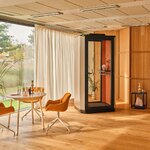 Cabine acoustique individuelle beige à intérieur corail dans un espace de pause avec table ronde