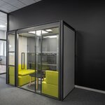 Cabine de réunion à porte coulissante vitrée avec banquettes jaunes dans un bureau