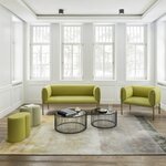 Canapé d'accueil 2 places vert olive sur pieds fins dans un salon lumineux, avec fauteuil assorti