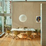 Table de réunion rectangulaire beige mat à pieds inclinés dans une salle lumineuse, entourée de fauteuils pivotants verts