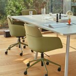 Angle dune grande table de réunion beige et pied incliné, avec fauteuils pivotants verts à roulettes