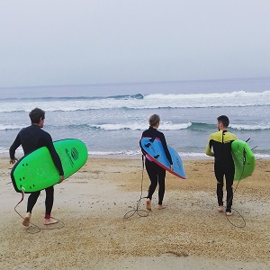 Trois surfeurs qui s'avancent dans la mer sur la plage de Biarritz