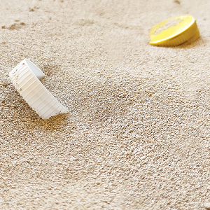 Deux bouchons de bouteilles en plastique à moitié dans le sable