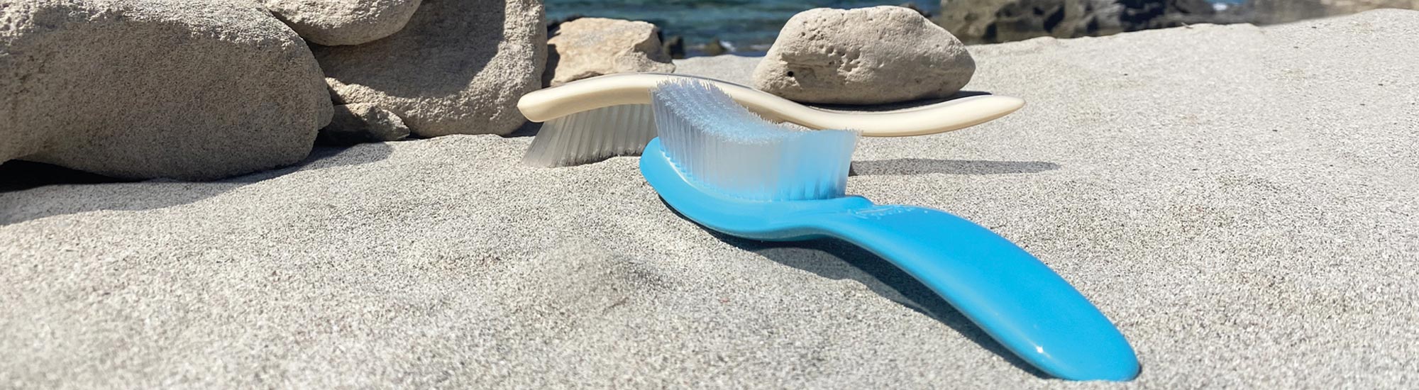 Deux brosses de plage sur le sable avec des rochers et la mer