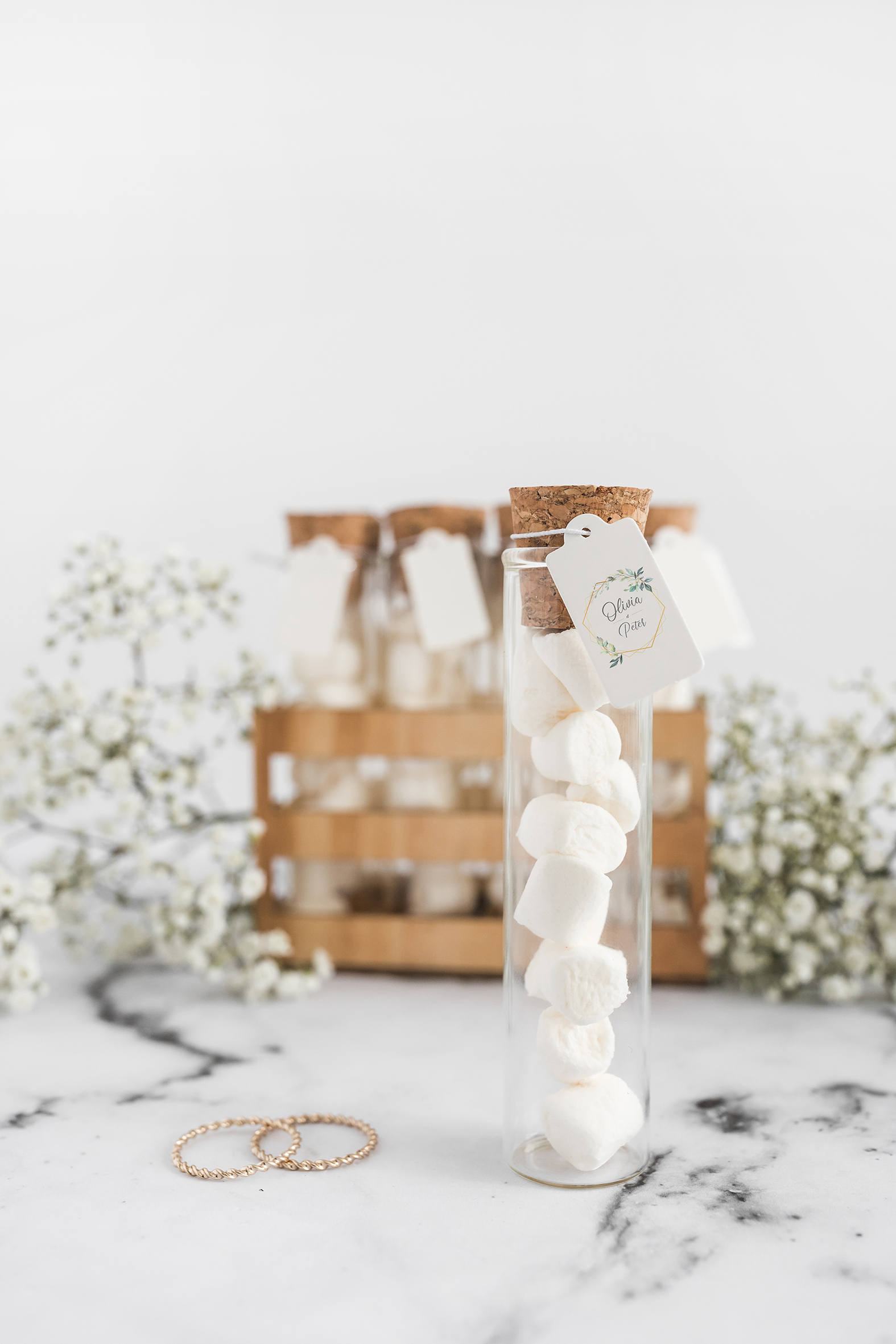 marshmallow-test-tube-with-blank-tag-wedding-rings-against-white-background