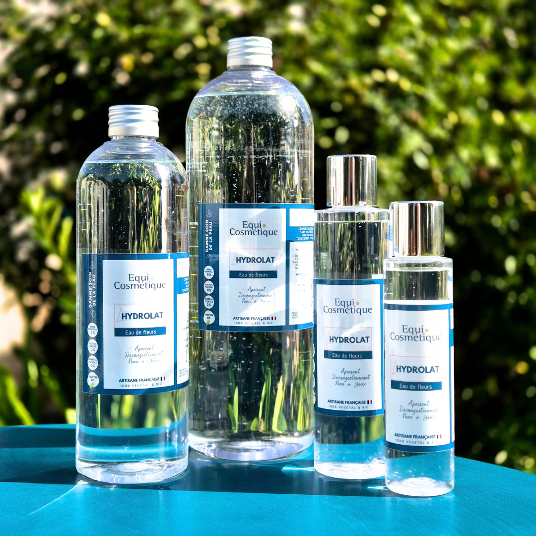 Flacons L’Hydrolat Equi Cosmétique en plusieurs formats, photographiés sur un fond végétal