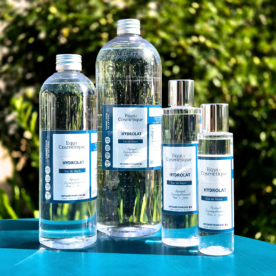 Flacons L’Hydrolat Equi Cosmétique en plusieurs formats, photographiés sur un fond végétal